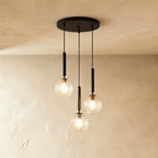 Clérachic three-head pendant on a round black canopy, with clear textured glass globes lit at staggered heights.