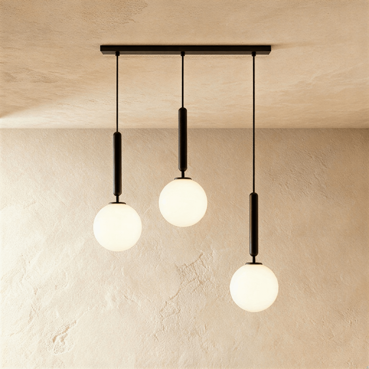 Clérachic three-head pendant on a long black bar, with milk white glass globes hanging at three staggered heights.
