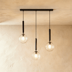 Clérachic three-head linear pendant on a black bar, with clear textured glass globes and lit bulbs at varied heights.