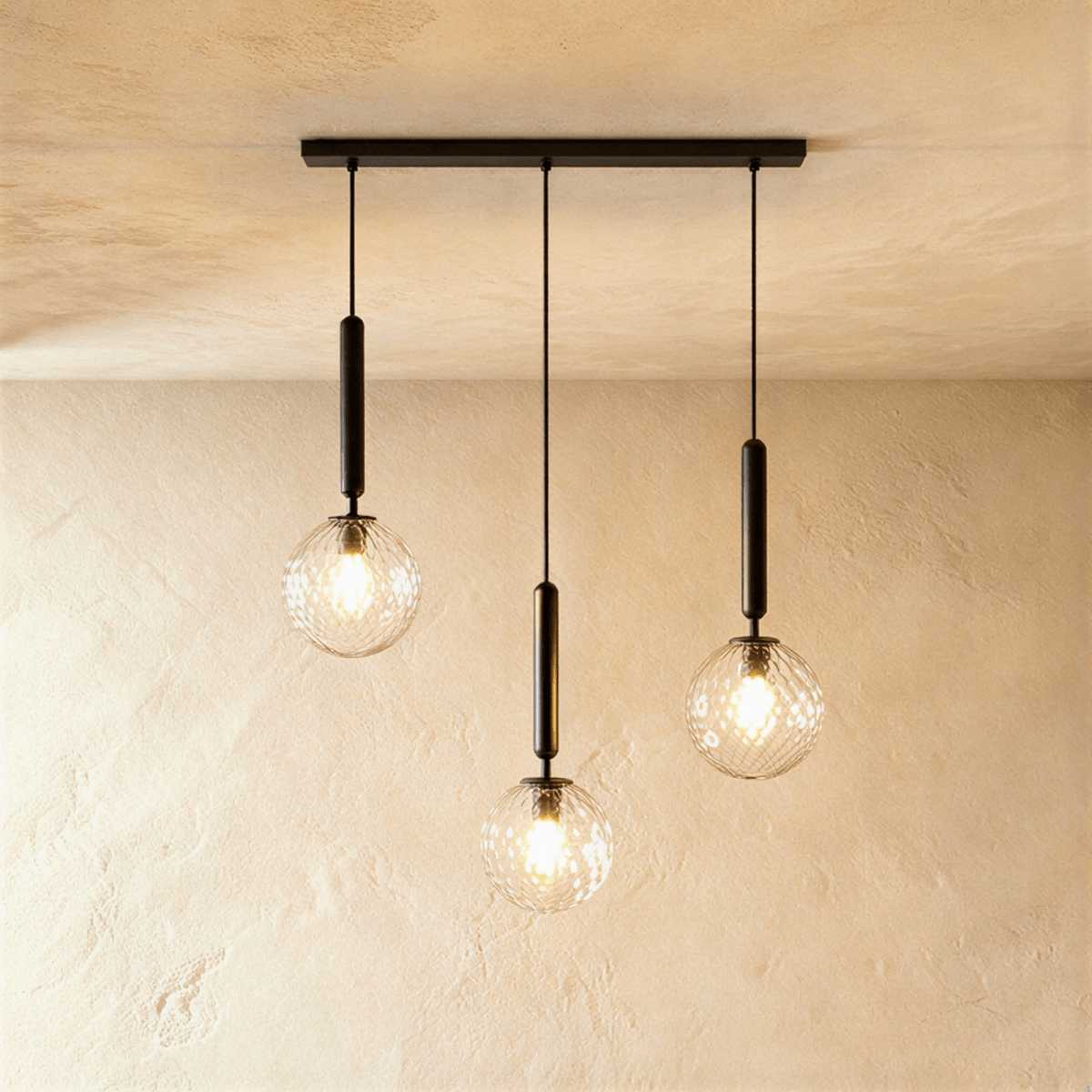 Clérachic three-head linear pendant on a black bar, with clear textured glass globes and lit bulbs at varied heights.