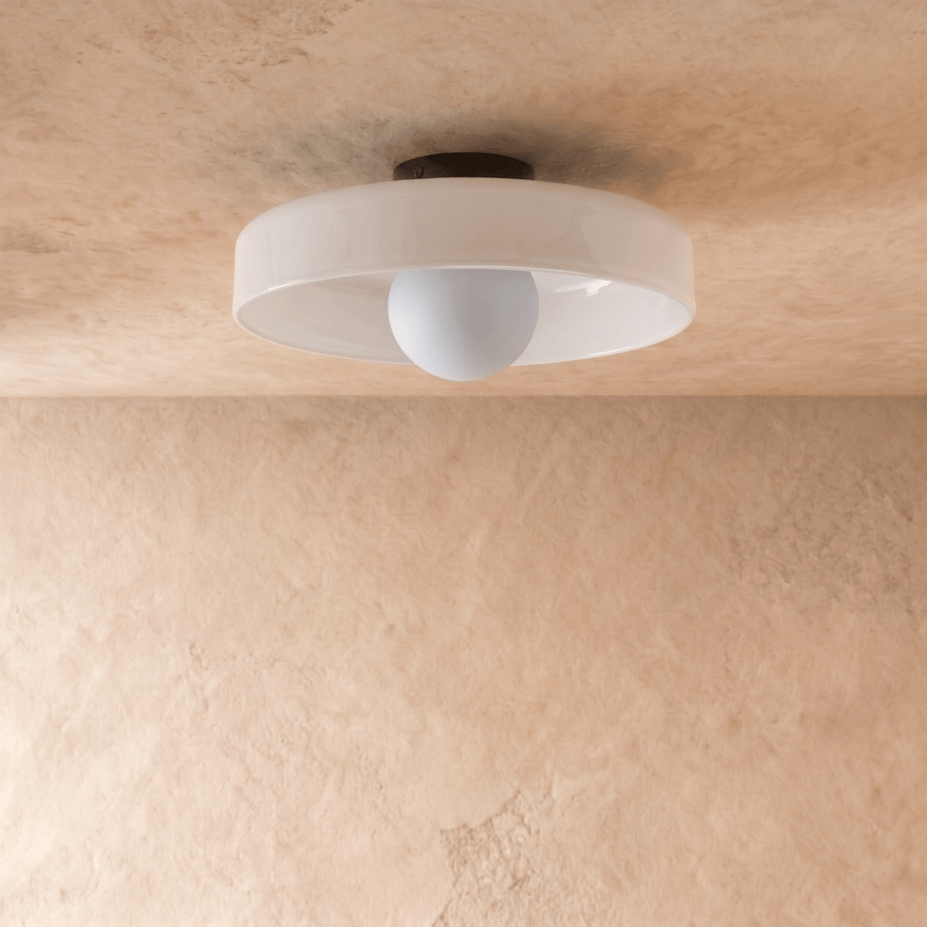 Clérachic shallow white glass disc ceiling light, switched off, showing a pale opal globe bulb and slim black canopy.