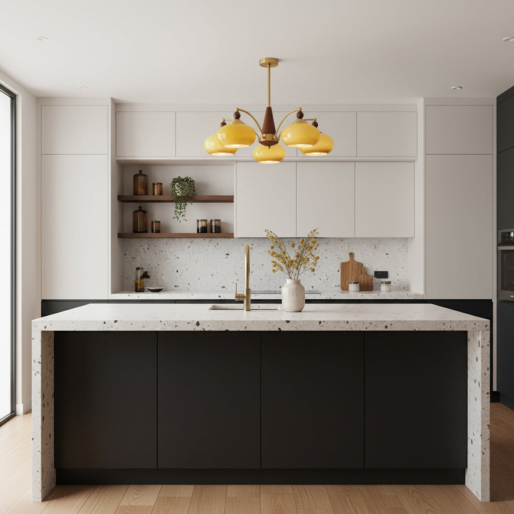 Caramel glass Clérachic chandelier hanging over a kitchen island with a speckled stone top, in a bright white kitchen.