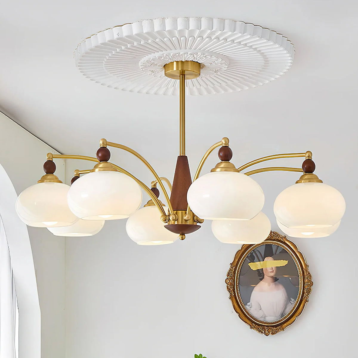 A white glass Clérachic chandelier hangs below a ceiling rose, with an oval framed portrait on the wall behind.