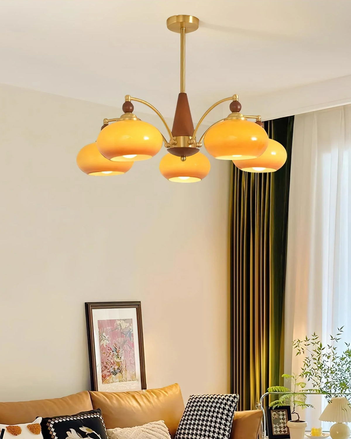 This Clérachic chandelier with caramel glass shades hangs above a living room with a tan sofa, green curtains and a framed print.