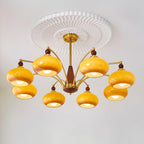 Eight caramel glass shades lit under a pleated white ceiling rose on this Clérachic chandelier, seen from below.