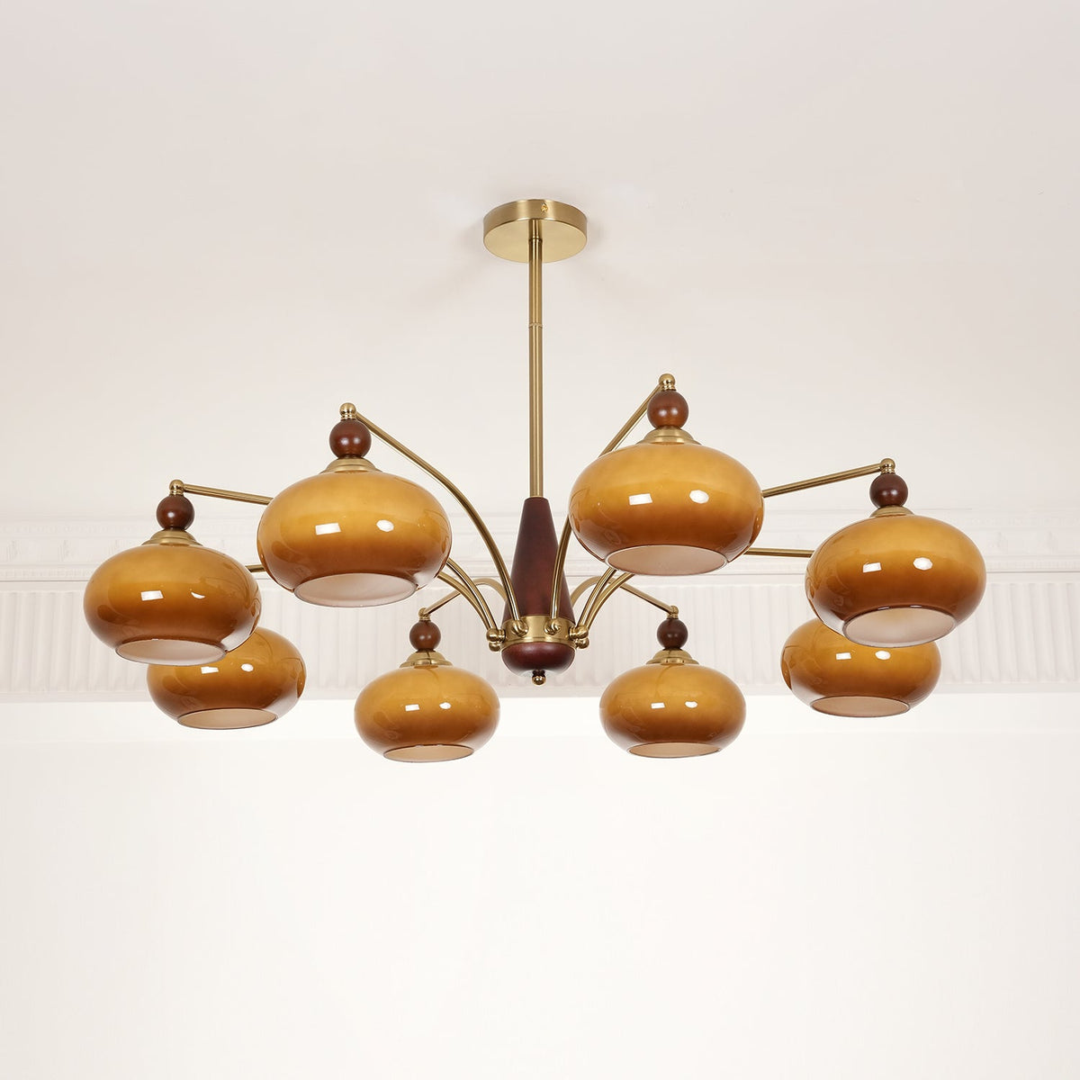 Unlit Clérachic chandelier with deep brown caramel glass shades on gold arms, hung against a white moulded ceiling.