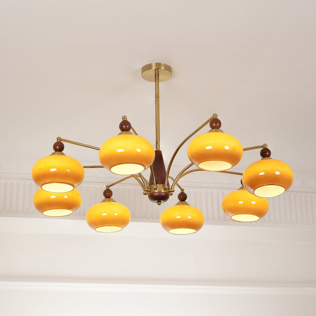 The same Clérachic chandelier switched on, with its caramel glass shades glowing bright yellow under the white ceiling.