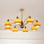 The same Clérachic chandelier switched on, with its caramel glass shades glowing bright yellow under the white ceiling.