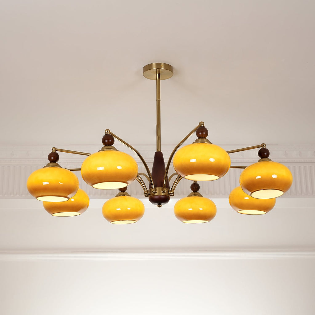 Lit Clérachic chandelier with eight caramel glass shades glowing yellow beneath a white moulded ceiling.