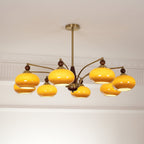 Side view of the lit Clérachic chandelier, its caramel glass shades glowing yellow on gold arms.