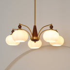 Close view of the lit white glass shades and walnut-toned wooden column of this Clérachic chandelier.