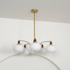 Side view of the unlit white glass Clérachic chandelier, hanging from a gold rod below a white ceiling.