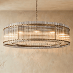 Clérachic widest drum chandelier of fluted glass rods with antiqued brass studs and a tiered inner ring, lit warm on a chain.
