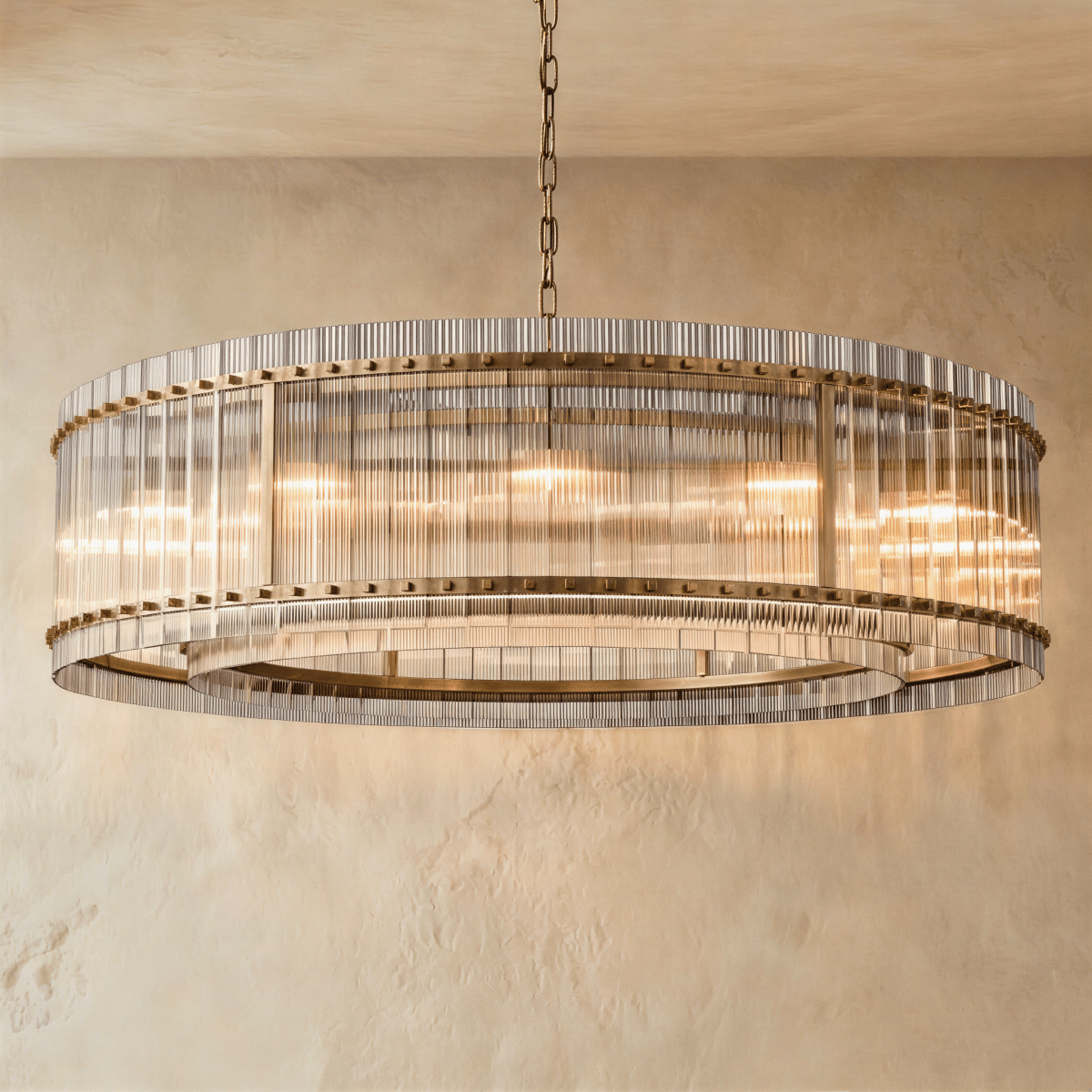 Clérachic widest drum chandelier of fluted glass rods with antiqued brass studs and a tiered inner ring, lit warm on a chain.