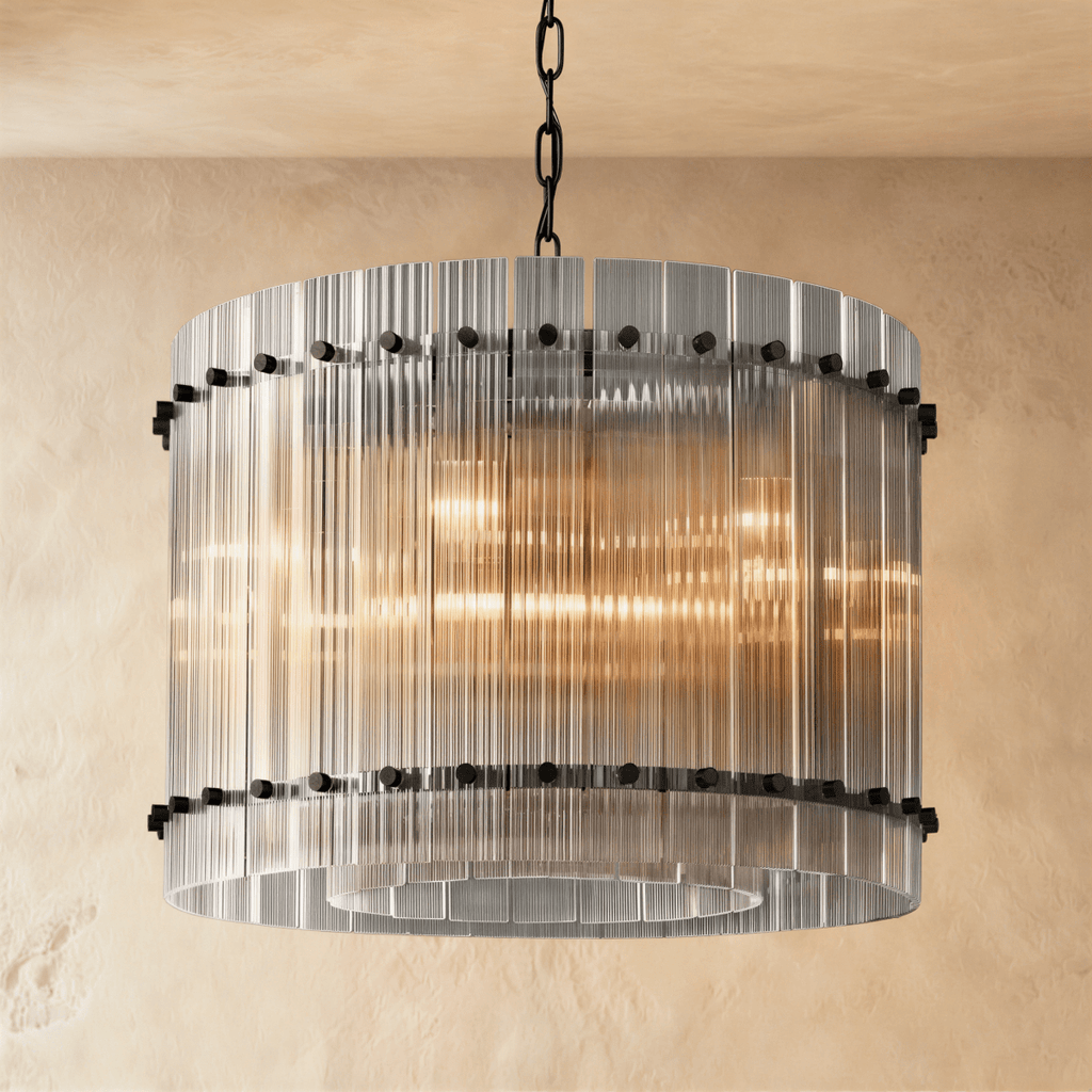 Clérachic compact drum chandelier of clear fluted glass rods with matte black studs on a chain, glowing against warm plaster.