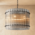 Clérachic compact drum chandelier of clear fluted glass rods with matte black studs on a chain, glowing against warm plaster.
