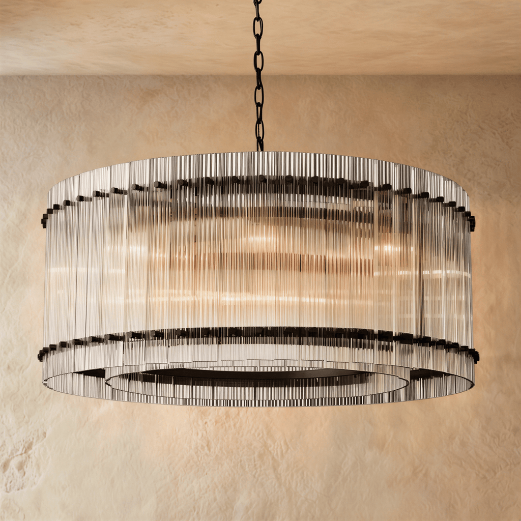 Clérachic wide drum chandelier of clear fluted glass rods with matte black studs, hung on a chain against warm plaster.