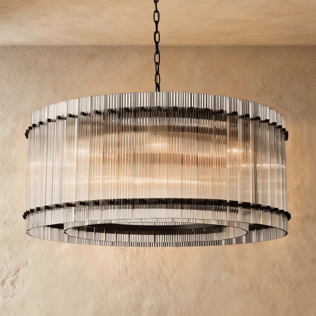 Clérachic wide drum chandelier of clear fluted glass rods with matte black studs, hung on a chain against warm plaster.