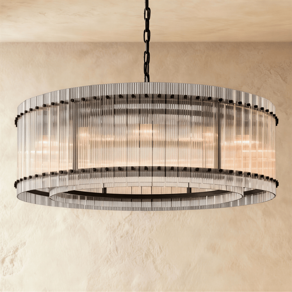 Clérachic larger drum chandelier of fluted glass rods with matte black studs and an inner ring, lit warm on a chain.