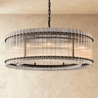 Clérachic larger drum chandelier of fluted glass rods with matte black studs and an inner ring, lit warm on a chain.