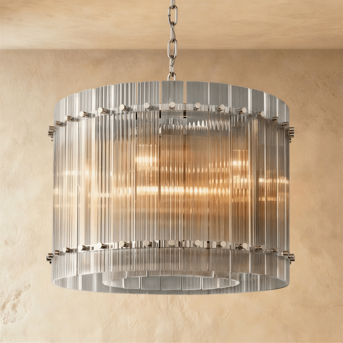Clérachic compact drum chandelier of clear fluted glass rods with polished nickel studs on a chain, glowing against warm plaster.
