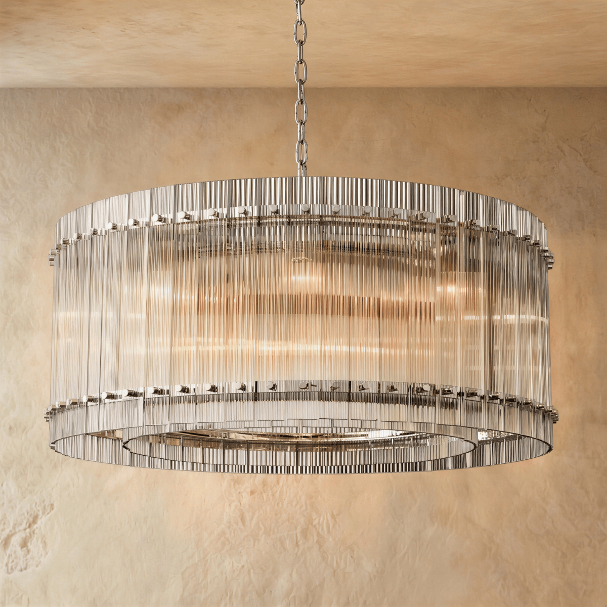 Clérachic wide drum chandelier of clear fluted glass rods with polished nickel studs, hung on a chain against warm plaster.