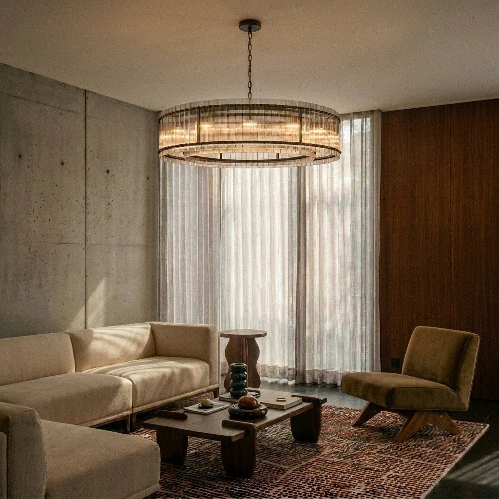 Clérachic large fluted glass drum chandelier hanging over a cream sofa and low wooden table in a concrete-walled living room.