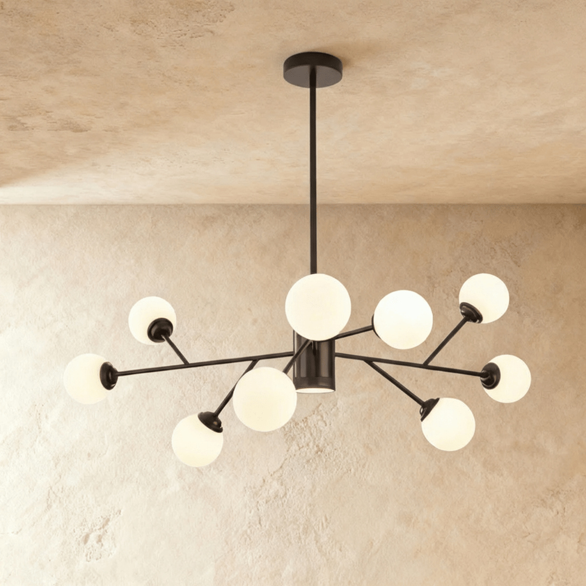 Clérachic branching chandelier in matte black, opal glass globes on angled arms against a plaster wall.