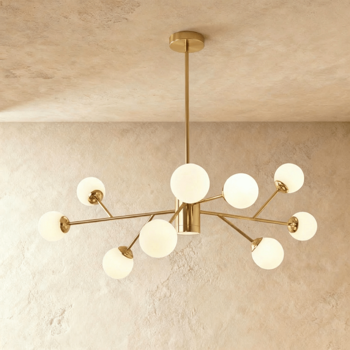 Clérachic branching chandelier in brushed gold, opal glass globes fanned on angled arms from a plaster ceiling.