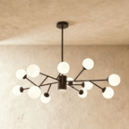 Clérachic branching chandelier in matte black, a denser cluster of opal glass globes spread wide and lit warm.