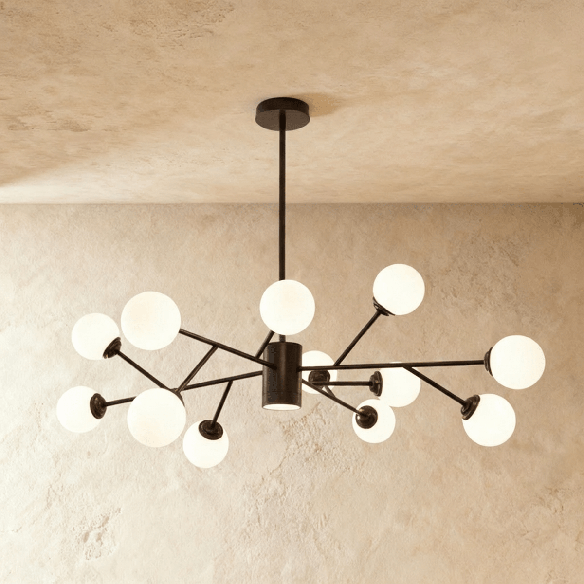 Clérachic branching chandelier in matte black, a denser cluster of opal glass globes spread wide and lit warm.
