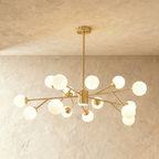 Clérachic branching chandelier in brushed gold, a dense cluster of opal glass globes lit warm on angled arms.