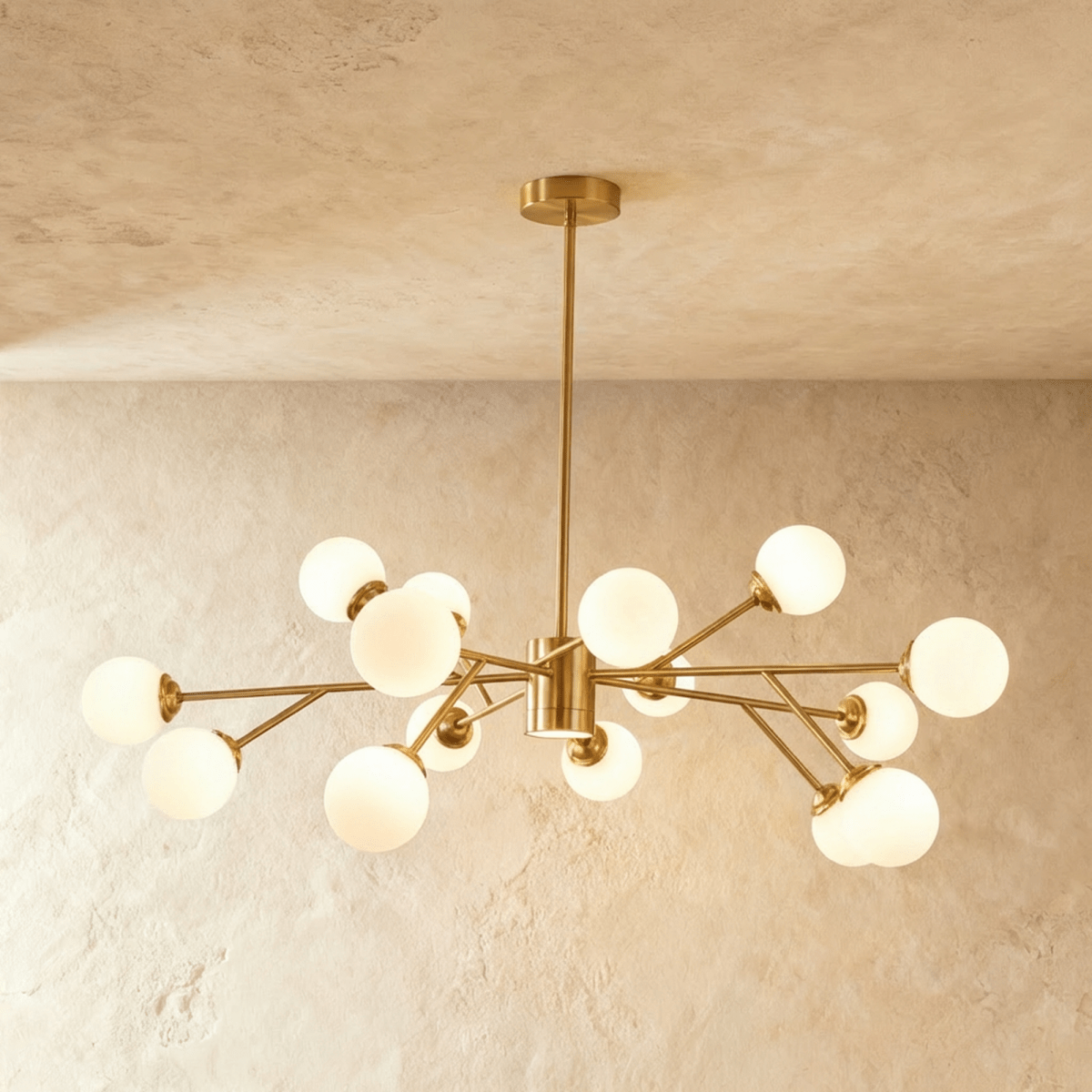 Clérachic branching chandelier in brushed gold, a wide dense spread of opal glass globes lit warm.