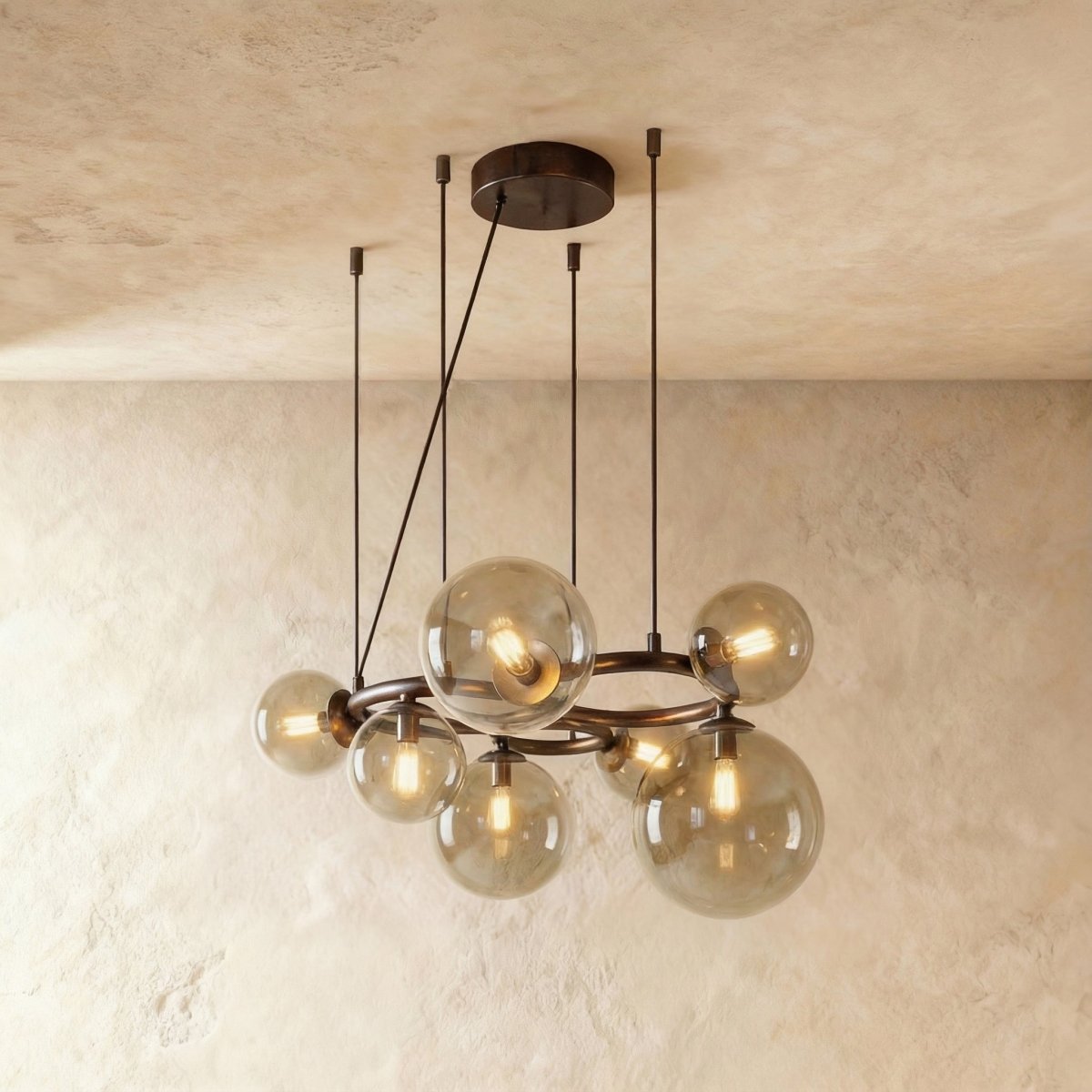 Clérachic globe cluster chandelier in Smoky Gray Glass, tinted glass spheres on a dark ring against plaster.