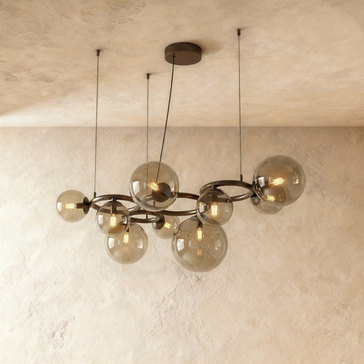 Clérachic globe cluster chandelier in Smoky Gray Glass, viewed from an angle showing its dark bronze ring frame.