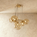 Clérachic globe cluster chandelier in Amber Glass, warm-tinted spheres clustered on a brass ring frame.