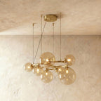 Clérachic globe cluster chandelier in Amber Glass, warm-toned spheres glowing softly on its brass ring frame.