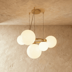 Clérachic globe cluster chandelier in Milk White Glass, its opaque spheres grouped on a brass ring seen from below.