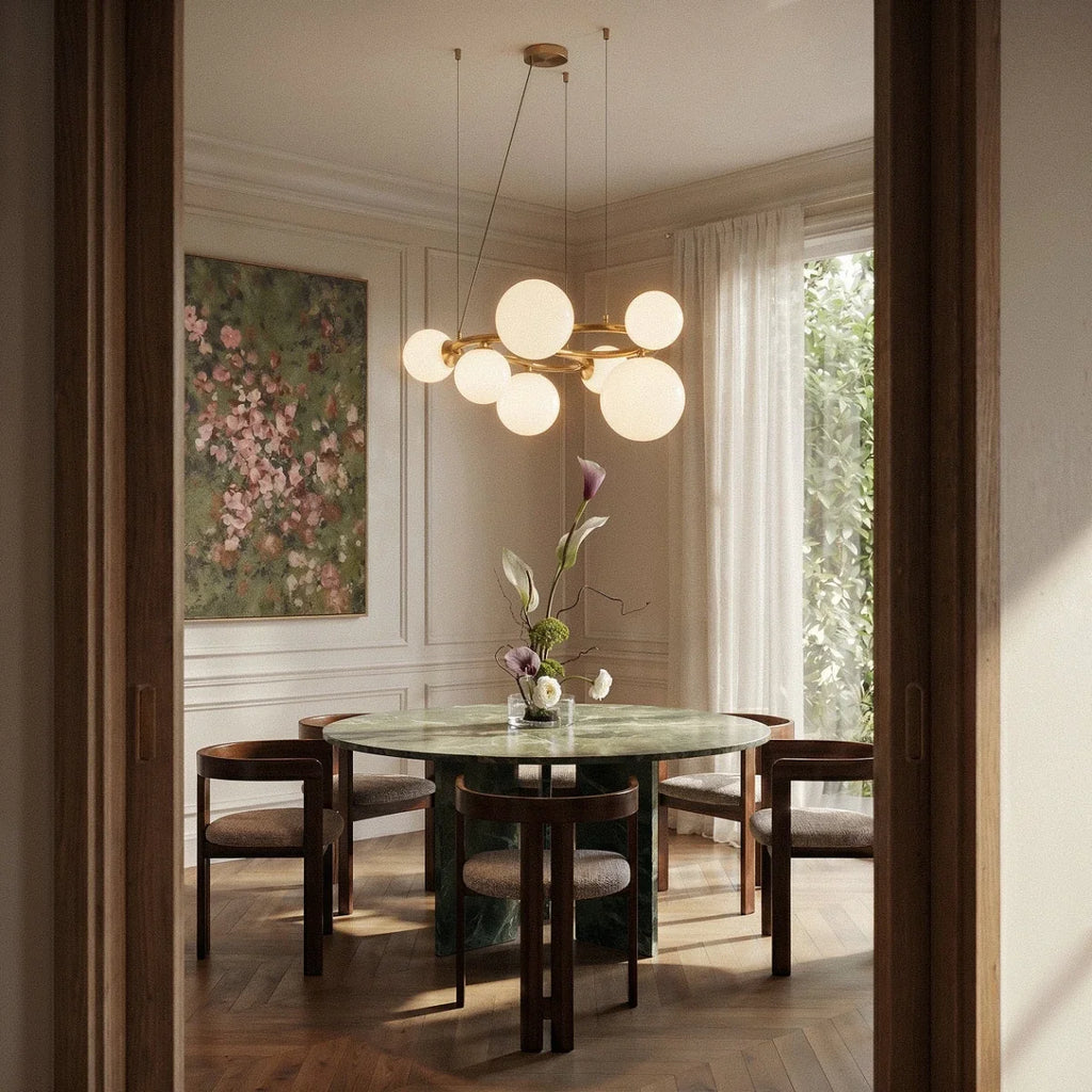 Clérachic globe cluster chandelier in Milk White Glass hangs above a round marble dining table in a panelled room.
