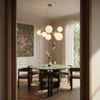Clérachic globe cluster chandelier in Milk White Glass hangs above a round marble dining table in a panelled room.