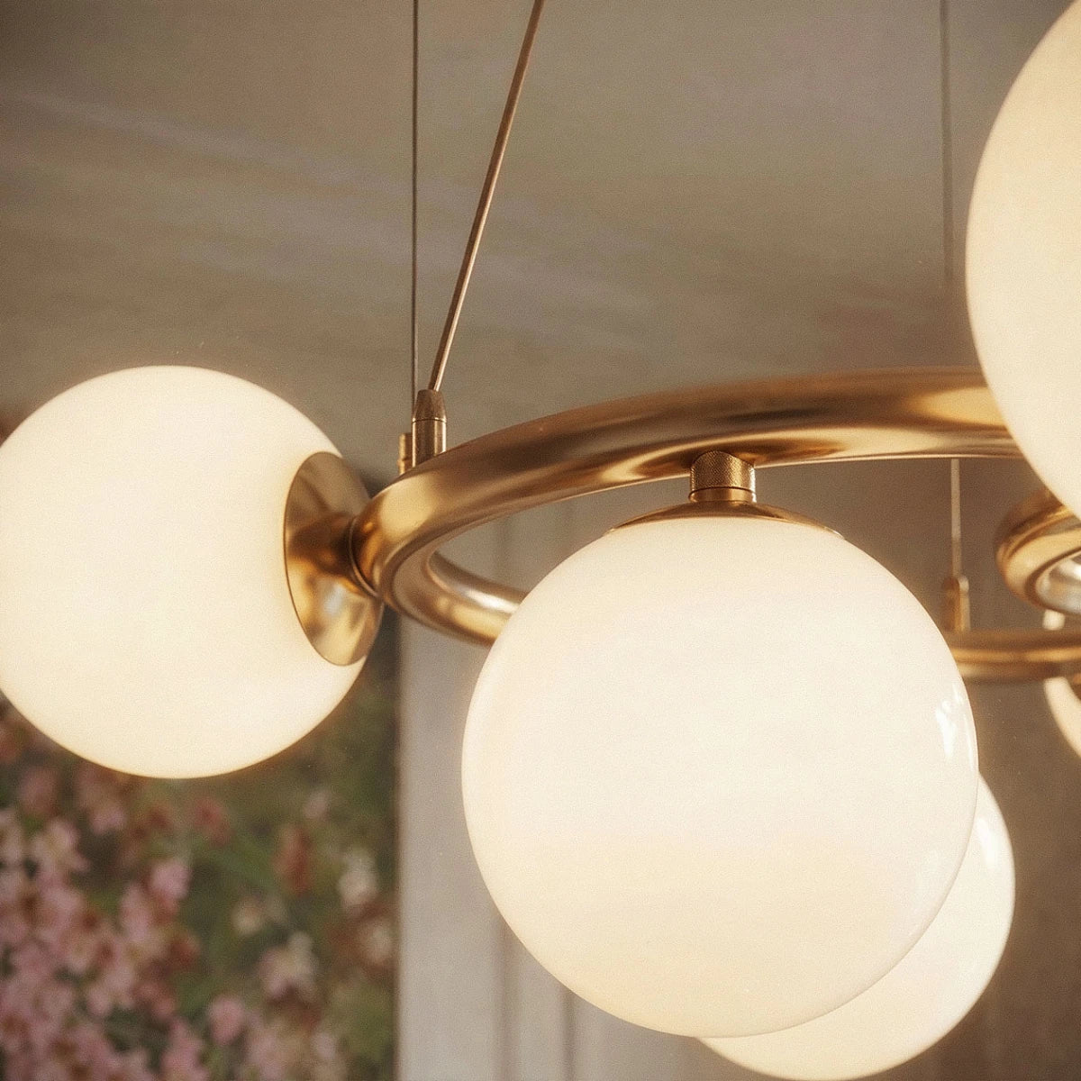 Close-up of the Clérachic globe cluster chandelier's Milk White Glass spheres and brushed brass ring joints.