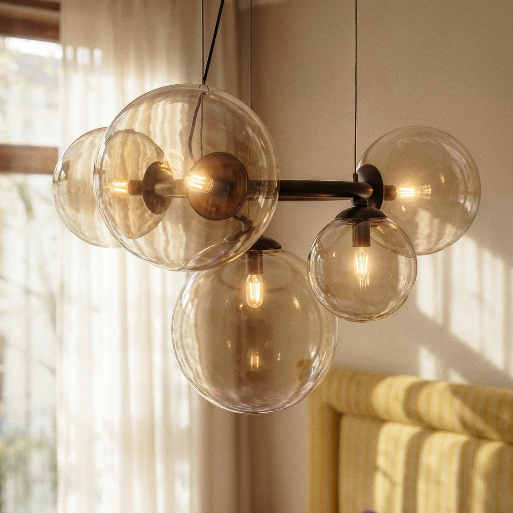 Close-up of the Clérachic globe cluster chandelier's Clear Glass spheres, warm bulbs glowing on a dark ring frame.