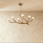 Clérachic branch chandelier in aged bronze, frosted glass globes lit warm along its sculpted arms.