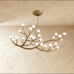 Clérachic branch chandelier densely set with frosted glass globes, lit warm across sweeping bronze branches.