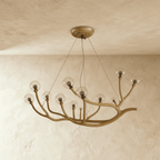 Clérachic branch chandelier in clear glass globes lit warm, bronze branches reaching from a plaster ceiling.