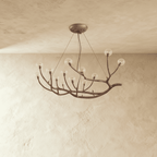 Clérachic branch chandelier in dark bronze with clear glass globes lit warm along its branching arms.