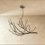 Clérachic branch chandelier in dark bronze, clear glass globes lit warm across its sprawling branches.