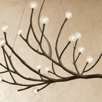 Clérachic branch chandelier detail, clear glass globes lit warm along the textured bronze branch arms.