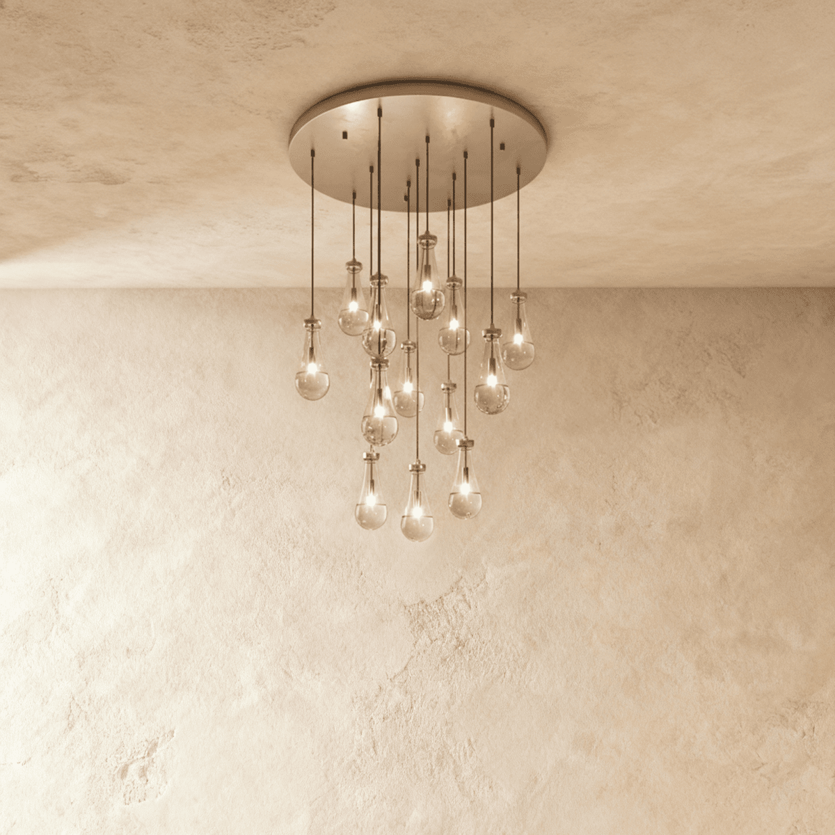 Clérachic chandelier with 13 clear glass teardrops on thin cords from a round satin nickel canopy, glowing warm, against limewashed plaster