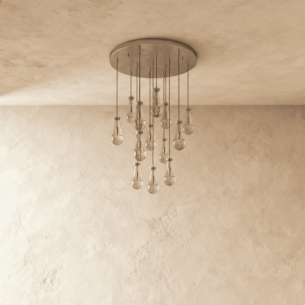 Clérachic chandelier with 13 clear glass teardrops on thin cords from a round satin nickel canopy, switched off, against limewashed plaster